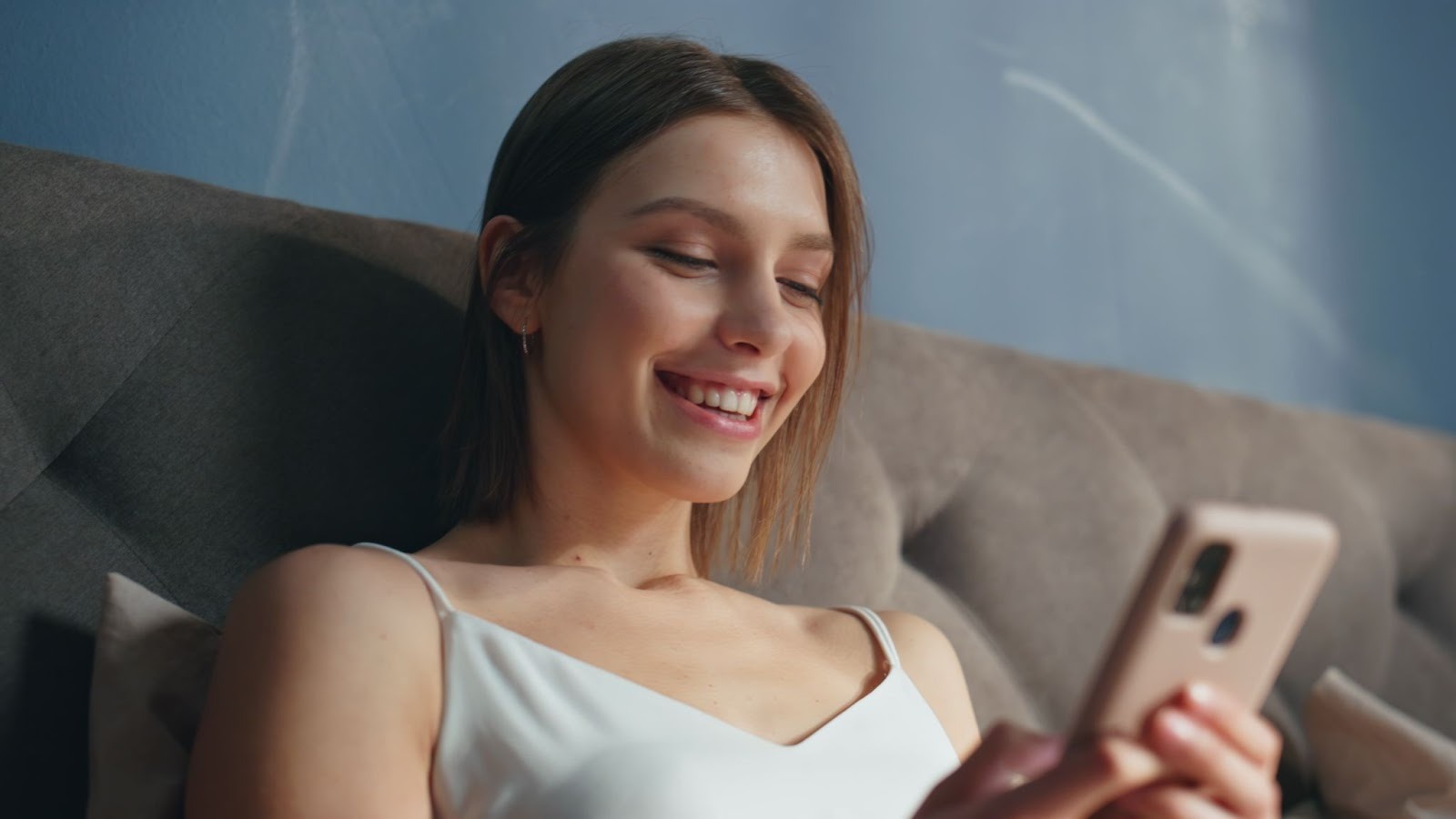 Женщина смеется над сообщением от парня, удачный вопрос в переписке
