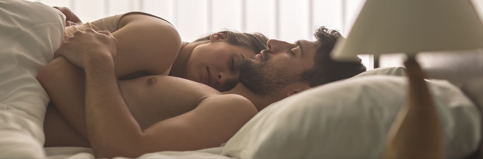 Мужчина обнимает девушку после интимной близости лёжа в кровати