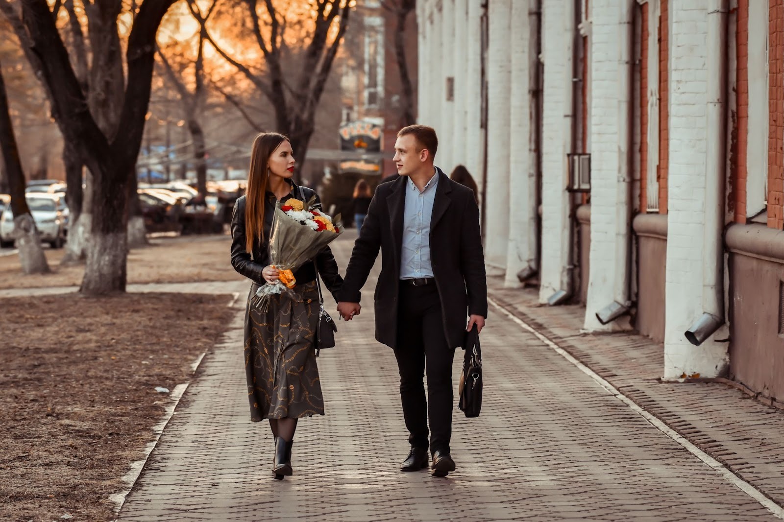 Молодая пара держится за руки во время прогулки по набережной
